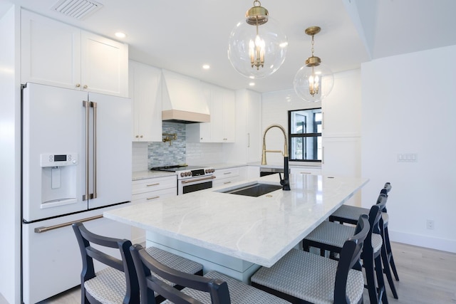 kitchen with white fridge with ice dispenser, white cabinetry, pendant lighting, and stainless steel range oven