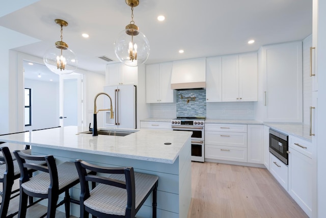 kitchen featuring white cabinets, custom range hood, appliances with stainless steel finishes, and decorative light fixtures