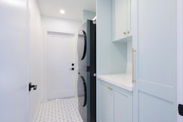 clothes washing area featuring cabinets and stacked washer / drying machine