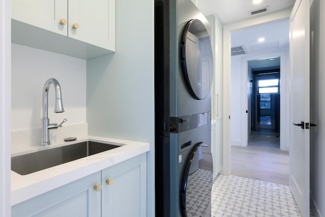 laundry room with light hardwood / wood-style floors, sink, and stacked washer and clothes dryer