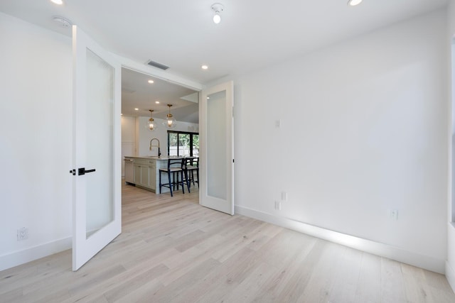 spare room featuring sink, french doors, and light hardwood / wood-style floors