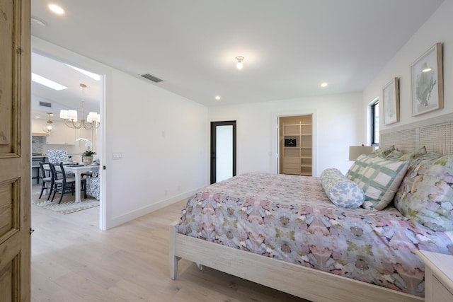 bedroom with an inviting chandelier, a closet, light hardwood / wood-style flooring, and a spacious closet