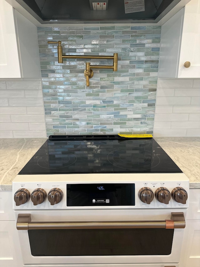 kitchen featuring backsplash, high end range, and white cabinets