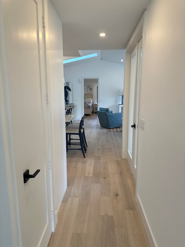 hall with light wood-type flooring and lofted ceiling