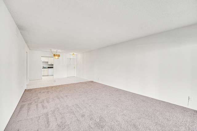 spare room with a textured ceiling and light carpet