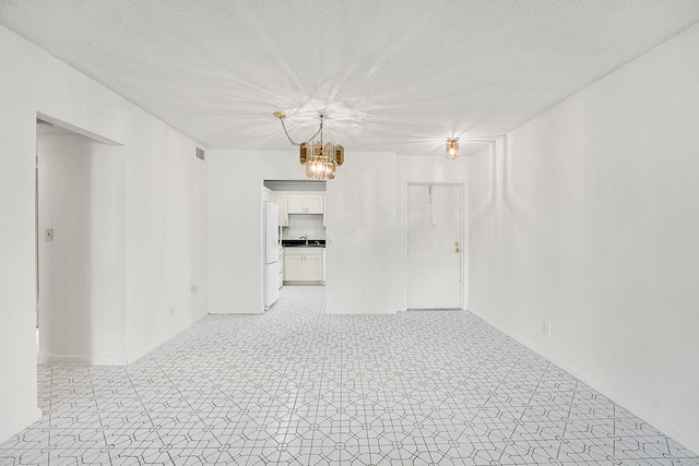 empty room with sink, a textured ceiling, and a notable chandelier