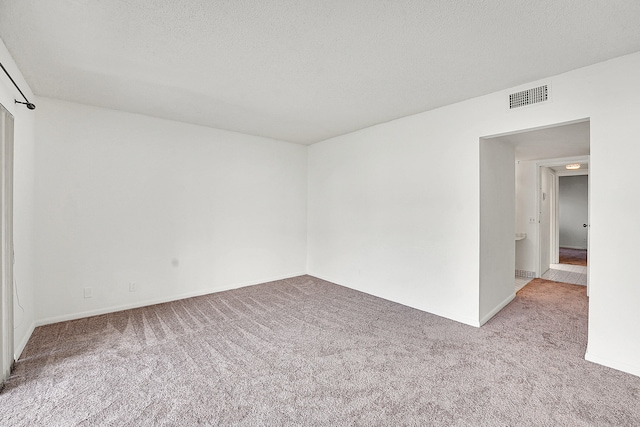 carpeted empty room featuring a textured ceiling