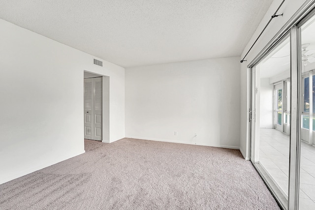 unfurnished room featuring a textured ceiling and light colored carpet