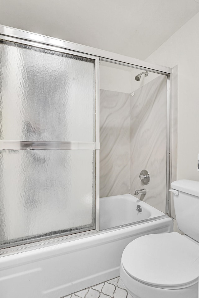 bathroom featuring tile patterned floors, combined bath / shower with glass door, and toilet