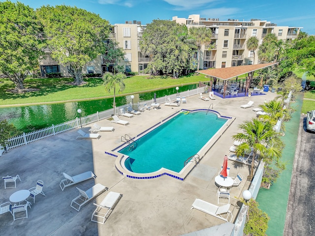 view of swimming pool featuring a patio area, a water view, and a yard