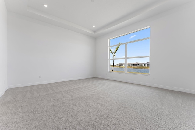 carpeted empty room with a tray ceiling