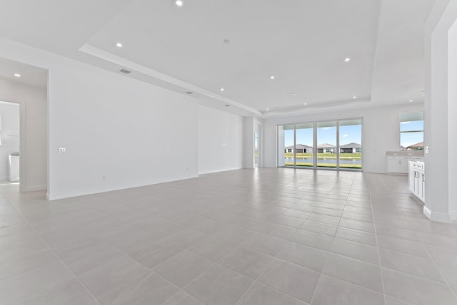 unfurnished living room featuring light tile patterned flooring and a raised ceiling