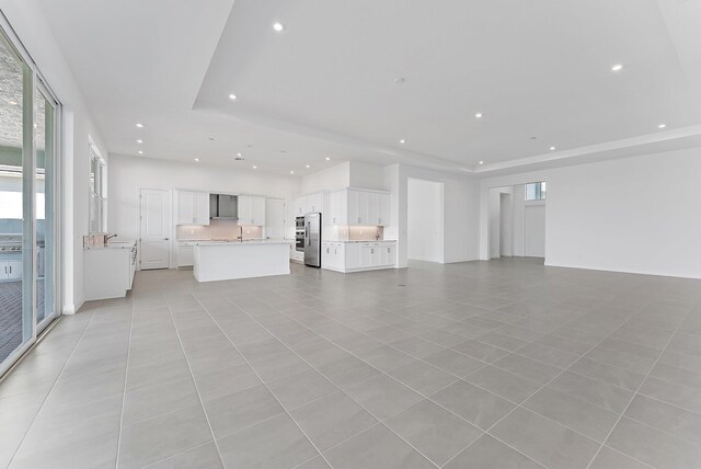 unfurnished living room with light tile patterned floors and a raised ceiling