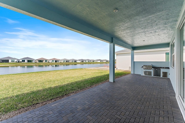 view of patio / terrace with area for grilling, a water view, and exterior kitchen