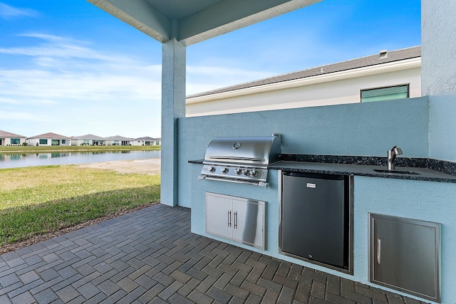 view of patio with a grill, a water view, area for grilling, and sink