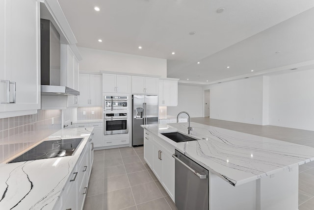 kitchen featuring white cabinetry, appliances with stainless steel finishes, wall chimney range hood, and light stone counters