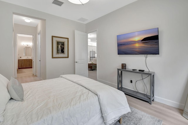 bedroom featuring light hardwood / wood-style flooring and ensuite bath