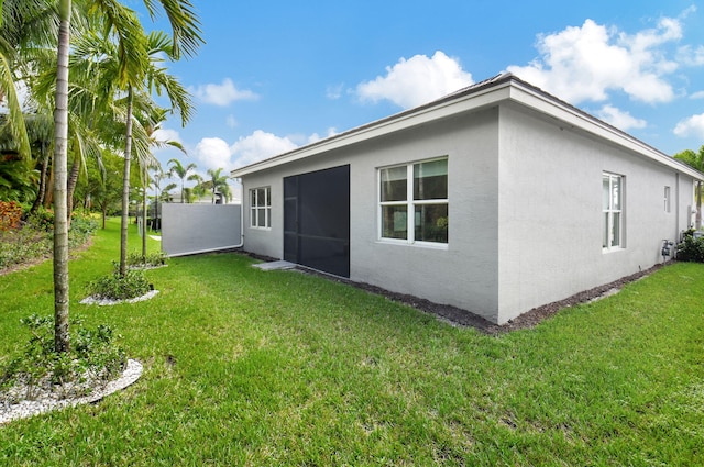 back of property with a sunroom and a lawn