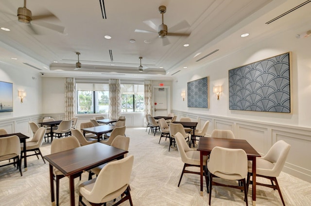 carpeted dining room with ornamental molding, a tray ceiling, and ceiling fan