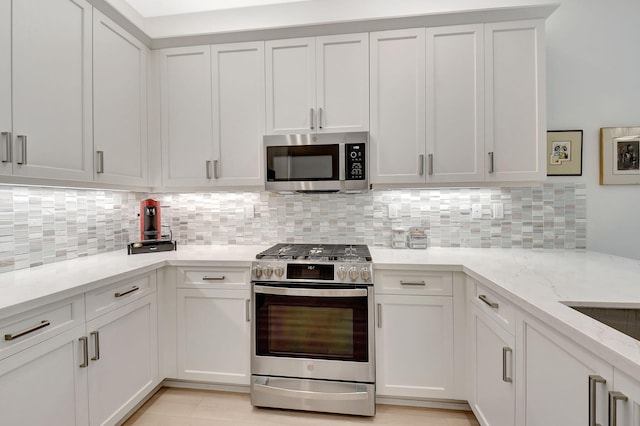 kitchen with white cabinetry, light stone counters, appliances with stainless steel finishes, and decorative backsplash