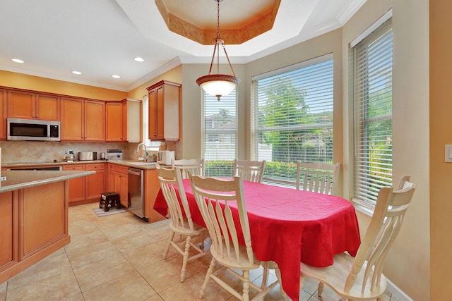 tiled dining room featuring sink, a tray ceiling, and ornamental molding