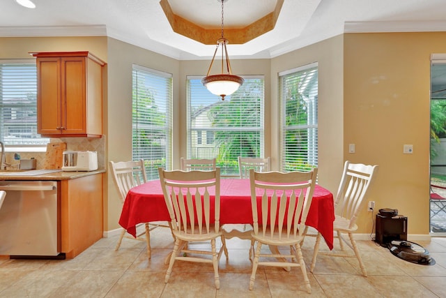 tiled dining area featuring a raised ceiling, crown molding, and a wealth of natural light