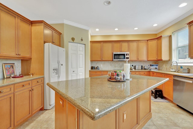 kitchen with appliances with stainless steel finishes, a kitchen island, light stone counters, and light tile patterned flooring