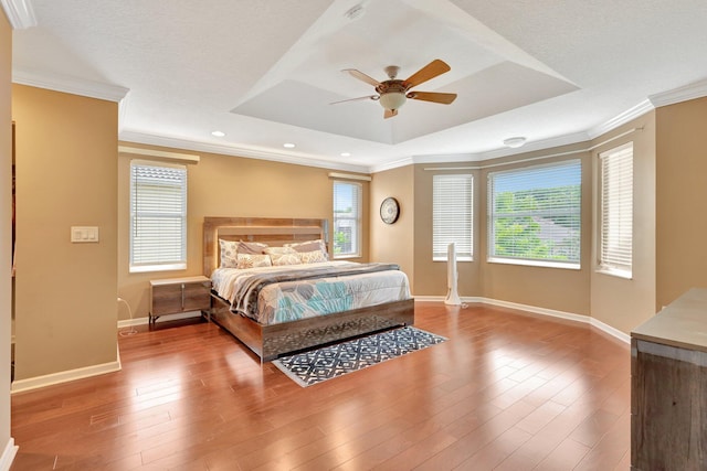 bedroom featuring ceiling fan, hardwood / wood-style flooring, a raised ceiling, and ornamental molding