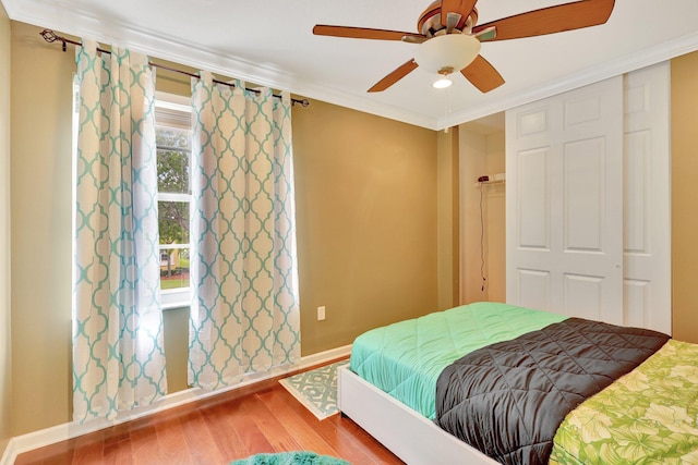 bedroom with wood-type flooring, a closet, ornamental molding, and ceiling fan