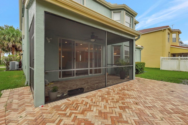 rear view of house with ceiling fan, a patio, a sunroom, central air condition unit, and a lawn