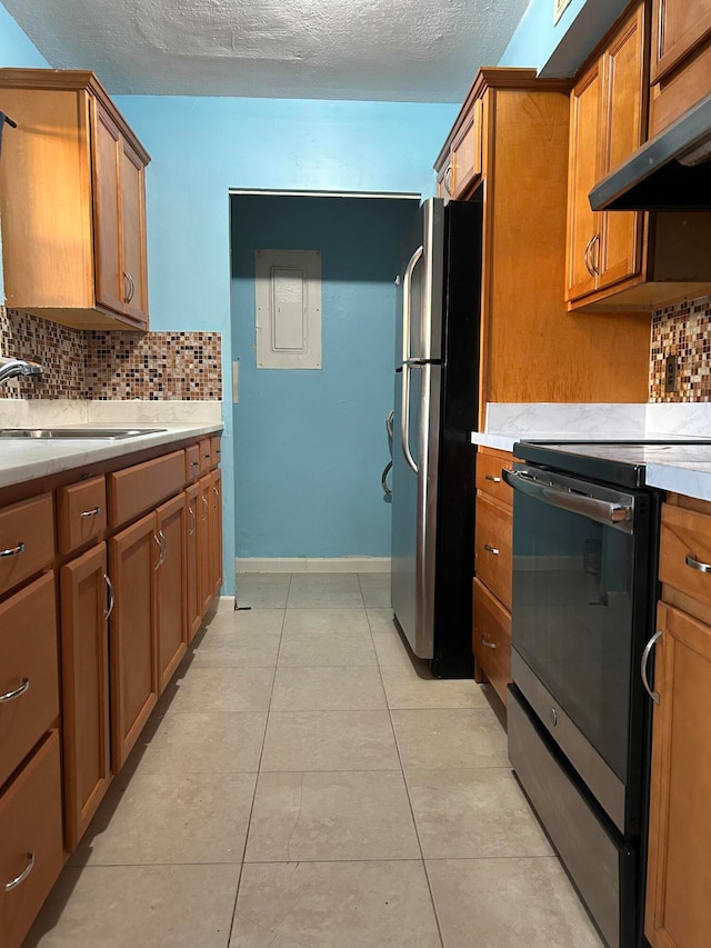 kitchen with tasteful backsplash, stainless steel refrigerator, extractor fan, and range