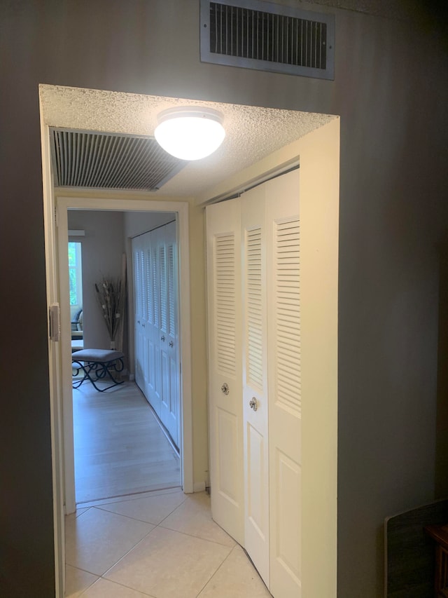 hall with light tile patterned flooring and a textured ceiling