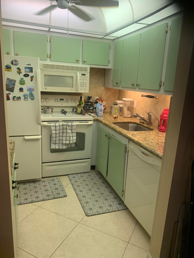 kitchen featuring white appliances, light stone countertops, light tile patterned floors, and sink