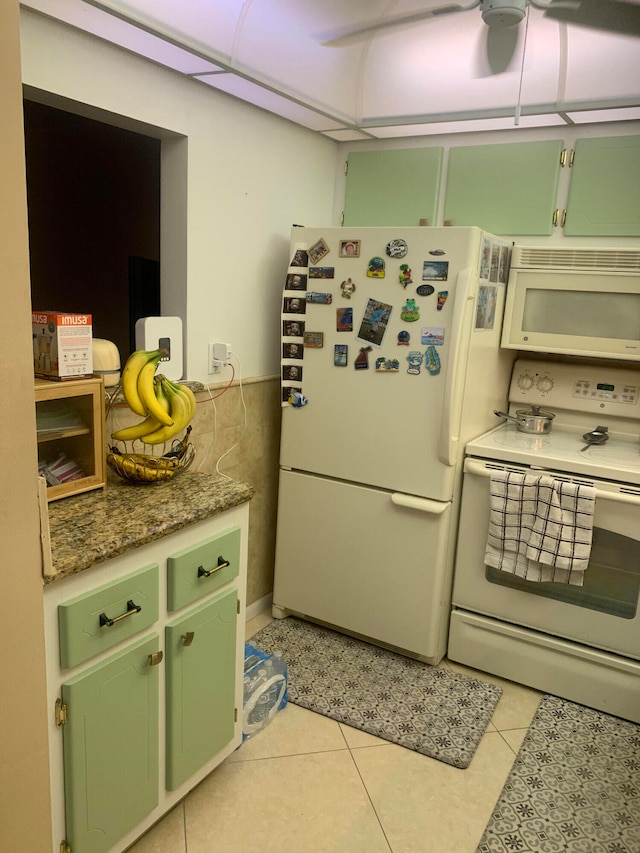 kitchen with green cabinets, stone countertops, light tile patterned floors, and white appliances