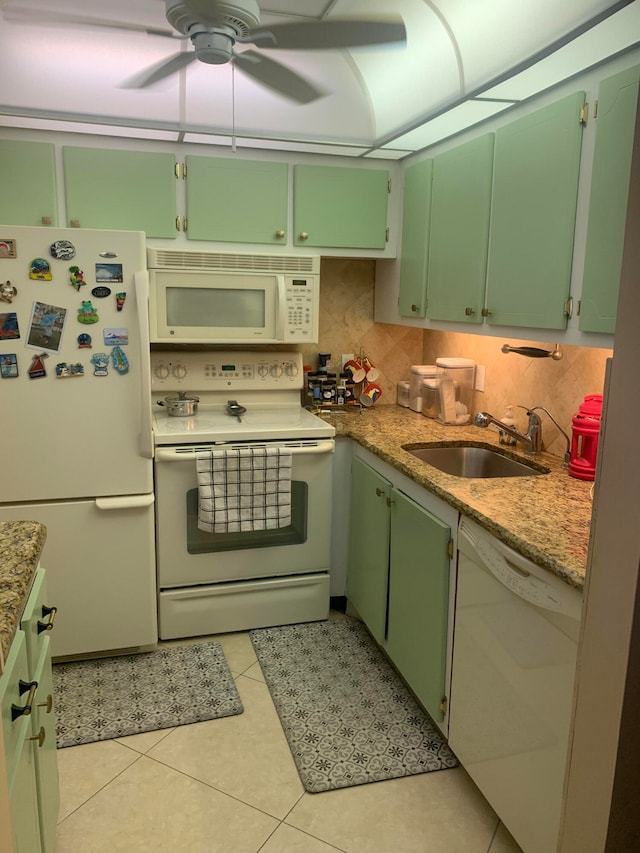 kitchen featuring decorative backsplash, sink, light tile patterned floors, light stone counters, and white appliances