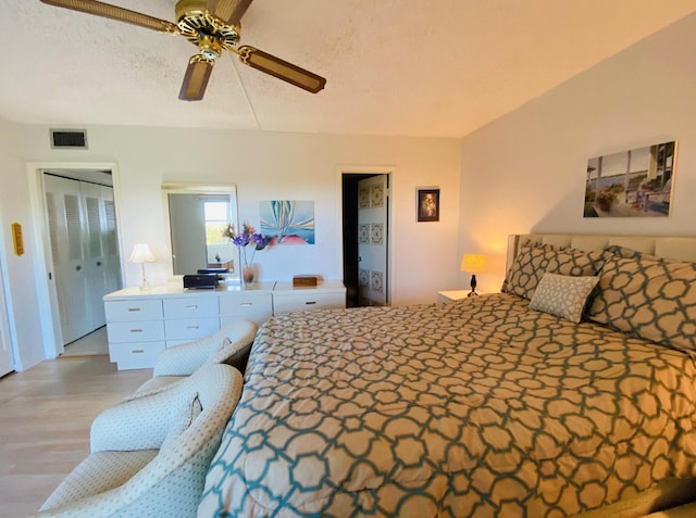 bedroom with light hardwood / wood-style floors, a textured ceiling, and ceiling fan