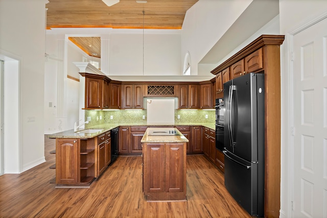 kitchen featuring black appliances, a kitchen island, backsplash, kitchen peninsula, and hardwood / wood-style flooring