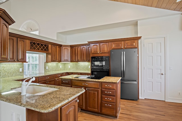 kitchen featuring light hardwood / wood-style flooring, vaulted ceiling, sink, a kitchen island, and black appliances