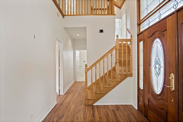 entrance foyer featuring wood-type flooring and a towering ceiling