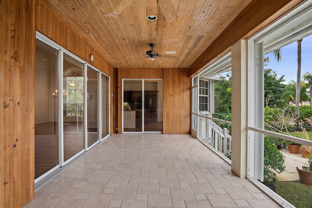 unfurnished sunroom with ceiling fan, wood ceiling, and a healthy amount of sunlight