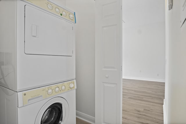 laundry area with stacked washing maching and dryer and light hardwood / wood-style floors