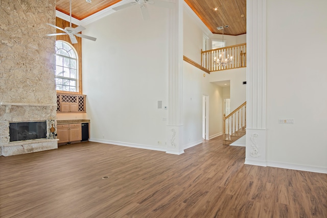 unfurnished living room featuring a high ceiling, hardwood / wood-style floors, a stone fireplace, and wood ceiling