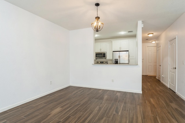 unfurnished living room featuring an inviting chandelier and dark wood-type flooring