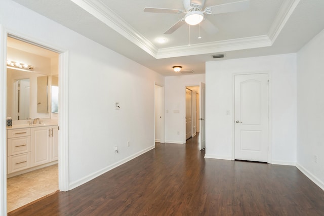 spare room featuring ornamental molding, ceiling fan, dark wood-type flooring, and a raised ceiling