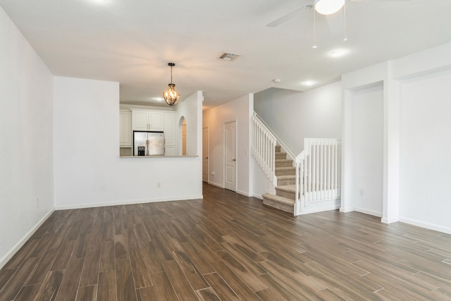 unfurnished living room with visible vents, baseboards, ceiling fan, dark wood finished floors, and stairs