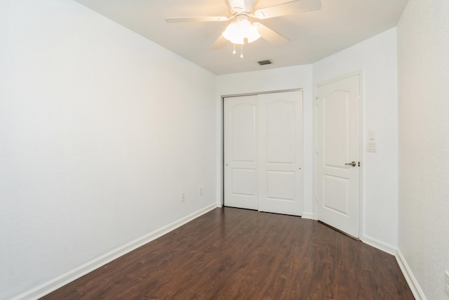 unfurnished bedroom featuring a closet, dark hardwood / wood-style flooring, and ceiling fan