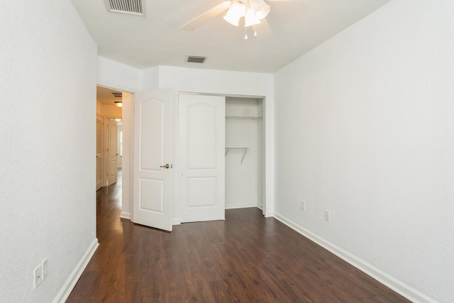 unfurnished bedroom with ceiling fan, a closet, and dark wood-type flooring