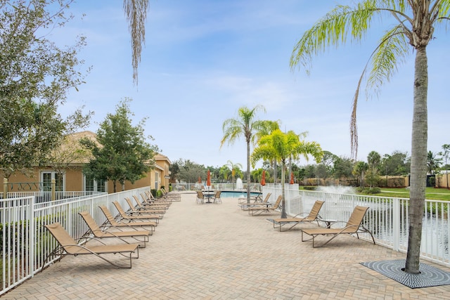 view of home's community with a water view, a swimming pool, and a patio area