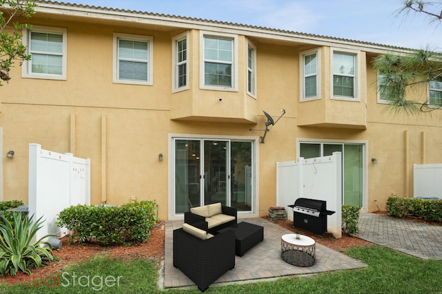 rear view of property with stucco siding, a patio, and fence