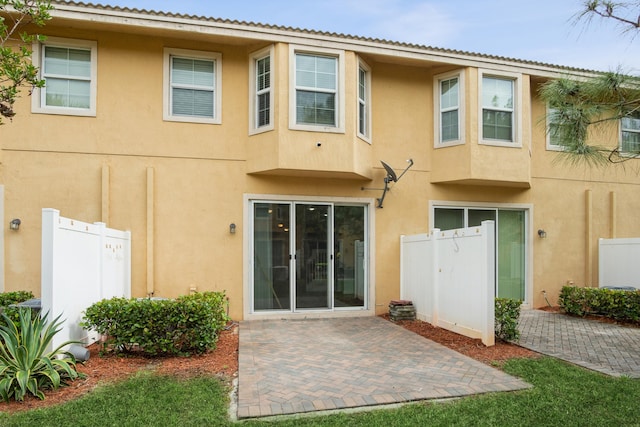 back of property featuring stucco siding, a patio, and fence